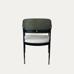 Elmor sırtı döşemeli kollu metal sandalye, koyu gri döşemeli geniş sırtlık ve açık renk oturma minderiyle siyah metal ayaklar üzerinde arkadan görünüm.
