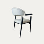 Beyaz döşemeli oturma ve sırt kısmına sahip, ince siyah metal ayaklı ve modern kol detayları bulunan Quatro metal sandalye – arka çapraz görünüm.
