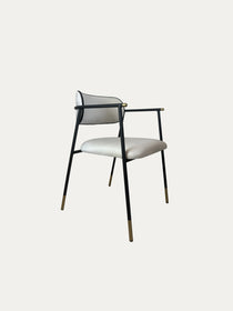 Sorel pirinç detaylı metal sandalye siyah ince metal gövde üzerine açık krem döşemeli oturum ve yuvarlak sırt tasarımıyla ön çapraz görünümde nötr arka plan üzerinde ürün fotoğrafı
